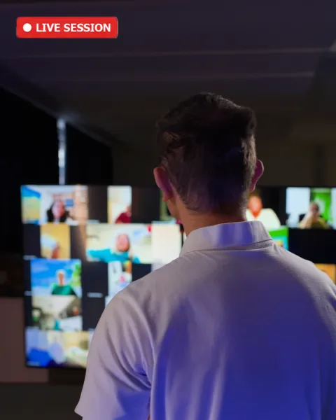 Jan von hinten vor den Bildschirmen mit den Teilnehmerinnen im Live-Webinar